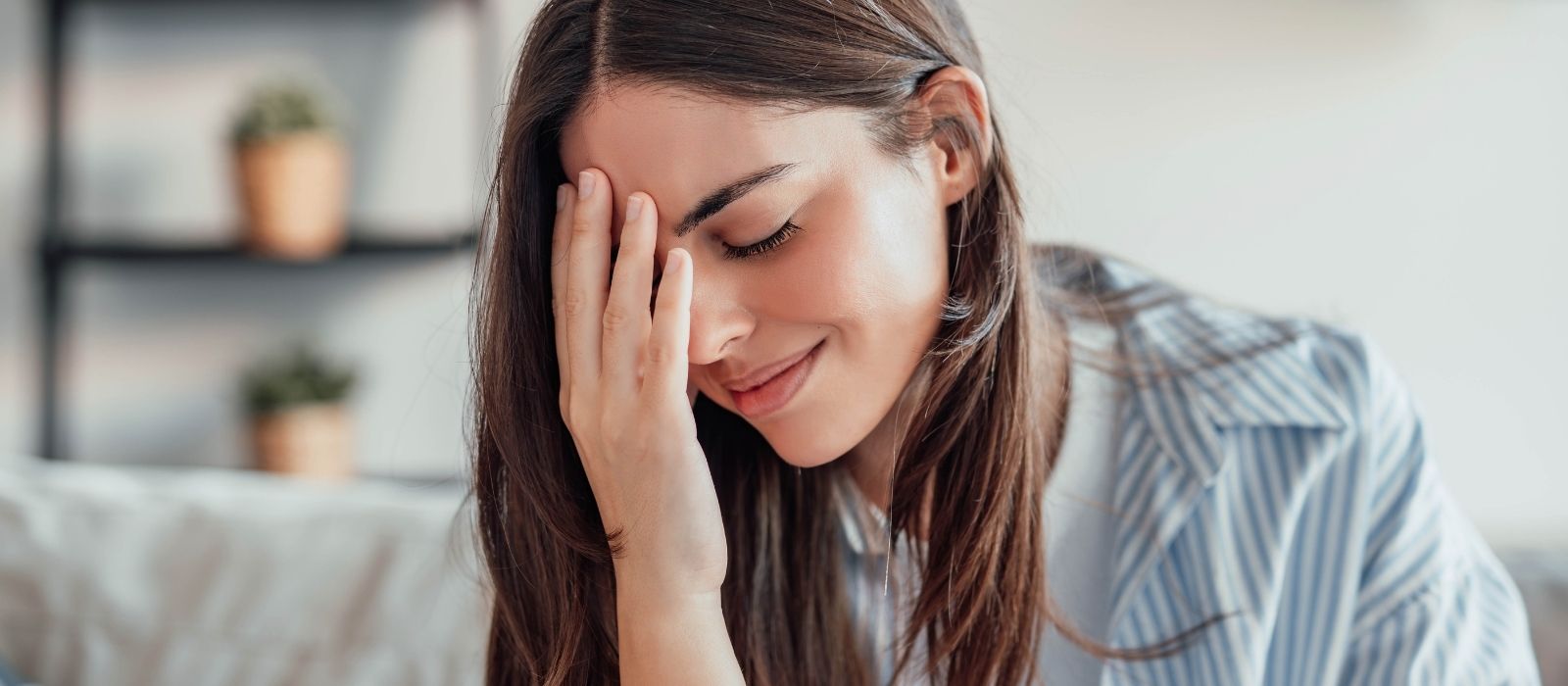 Tired woman with her hand over her eyes at home