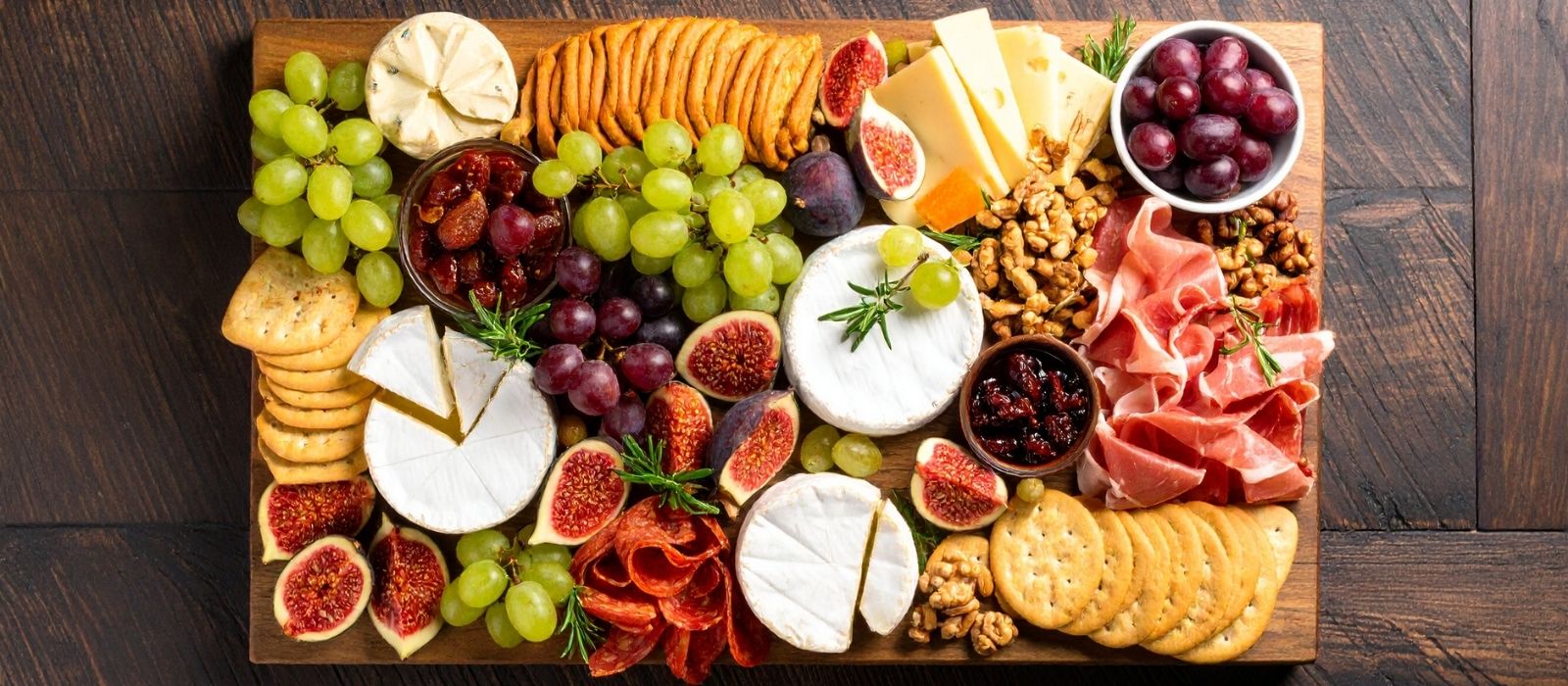 Overhead cheese board with figs, grapes, crackers and prosciutto