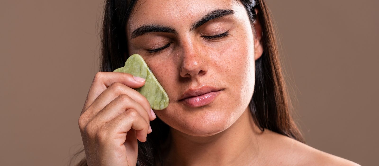 Woman performing gua sha facial massage