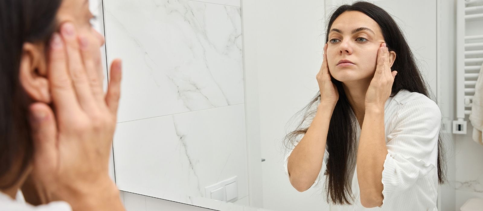 Woman examining clear skin in soft natural light