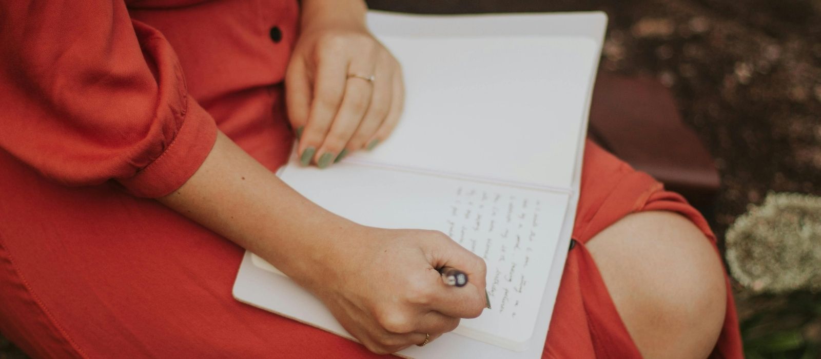 Woman writing in a journal by a window