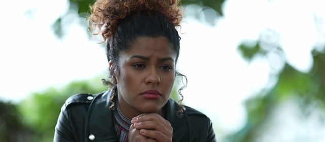 Worried woman outdoors with hands clasped under her chin