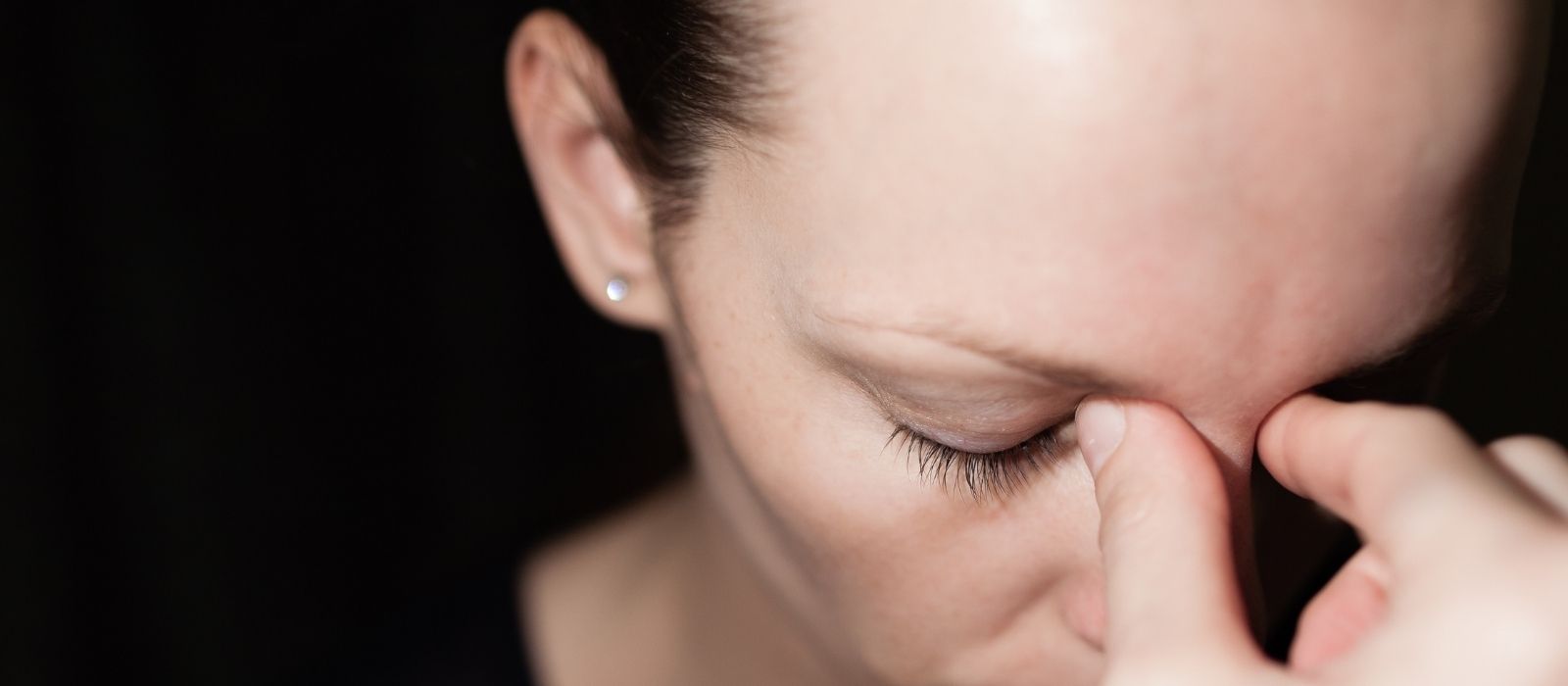 Woman with eyes closed pinching the bridge of her nose