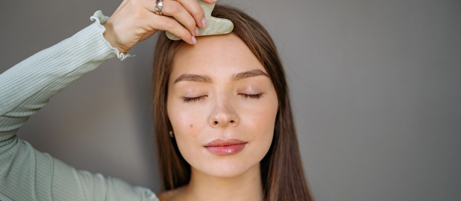 Woman performing gua sha facial massage