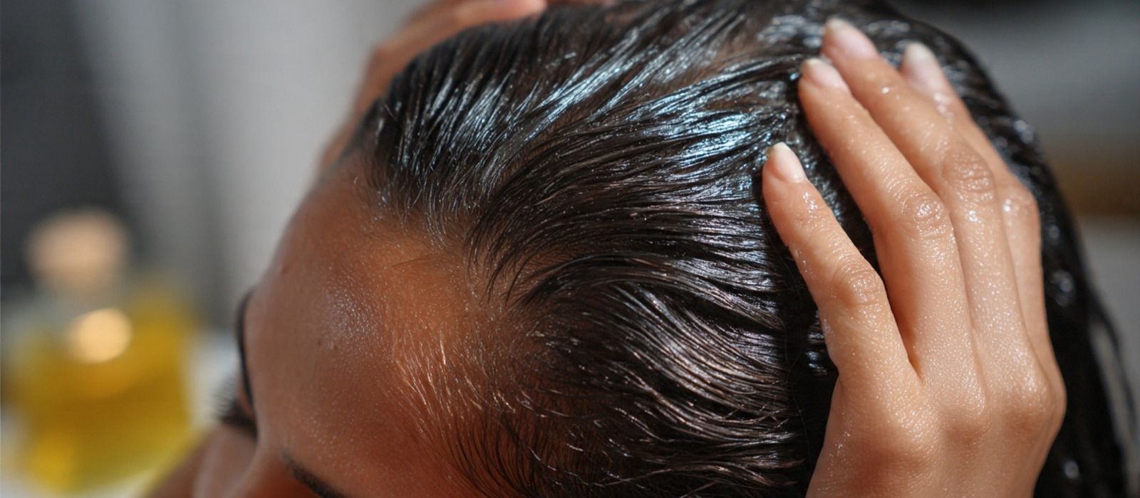Hair oil being applied to scalp in warm light