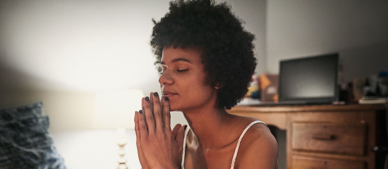Woman with eyes closed and hands pressed together