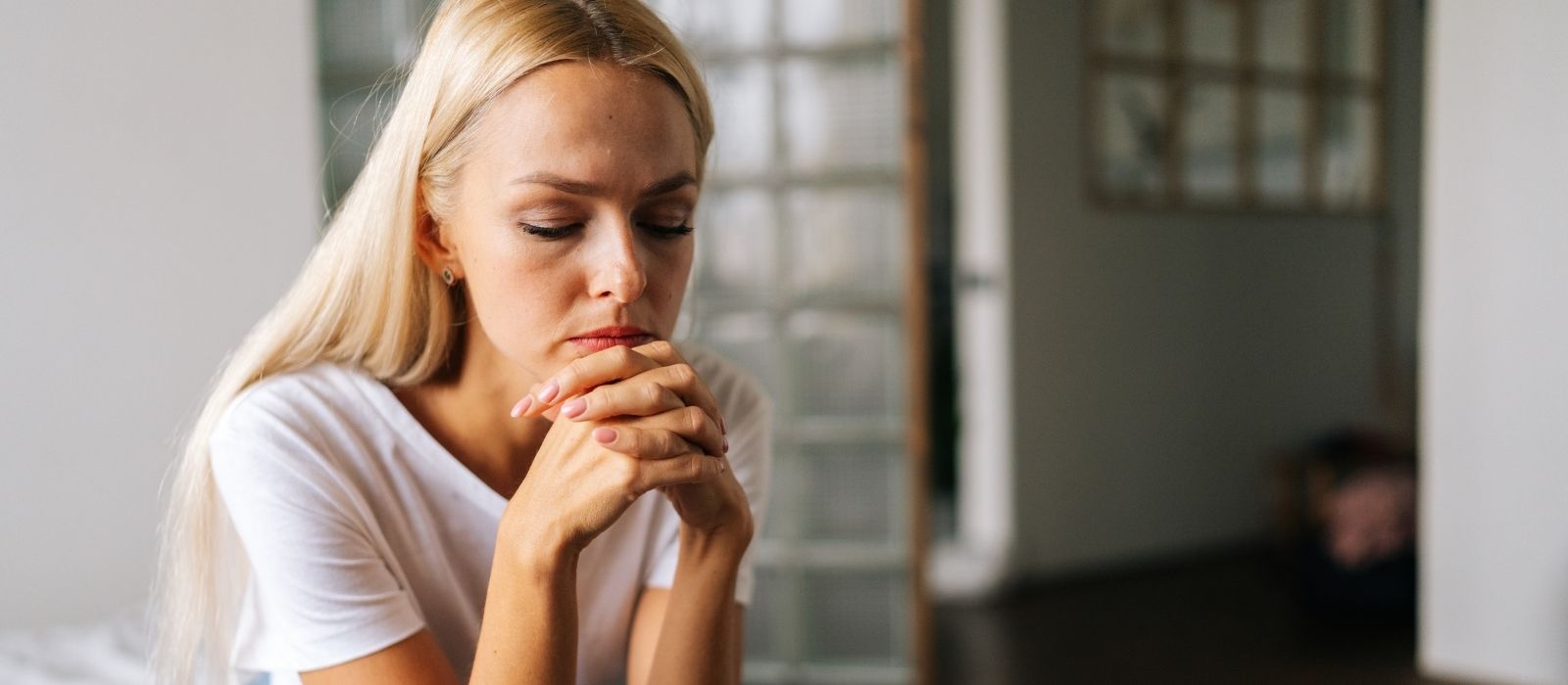 Woman with clasped hands and closed eyes at home