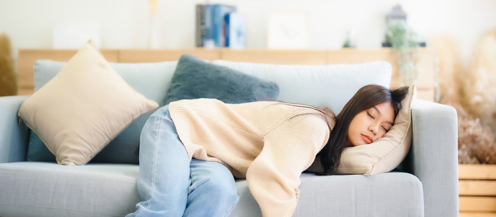 Woman asleep on a pale blue sofa with cushions