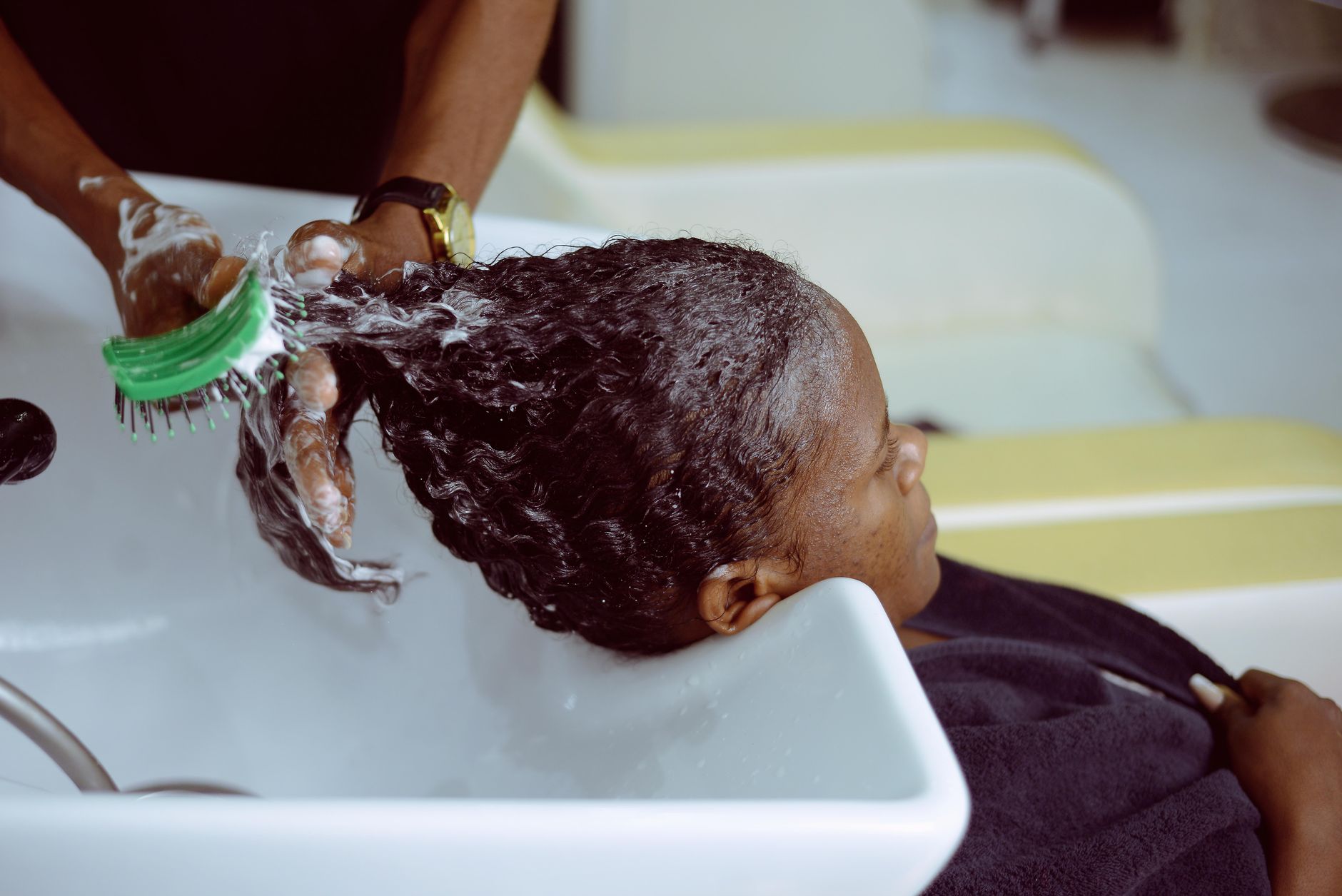 Woman gently massaging her scalp with fingertips near a window